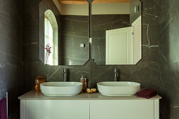 Waschtisch mit zwei Aufsatzbecken und Spiegeln im Badezimmer mit Marmorfliesen