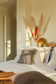 Pillows on a bed with decorative items on a shelf behind it in a bedroom