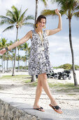 Brunette woman in printed summer dress on the beach