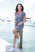 Brunette woman in a striped summer dress by the sea