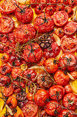 Preparing roasted tomato sauce from the oven - Tomatoes with garlic and herbs on a baking tray