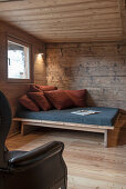 Sofa with cushions and leather armchair in a wooden hut