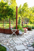 View over garden path of paving stones and concrete slabs to raised beds and fairy lights