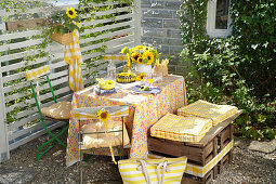 Gedeckter Tisch mit Sonnenblumenstrauß im Freien