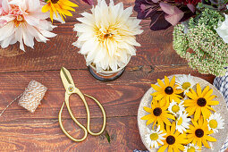 Flower arrangement with dahlias, rudbeckia and daisies on garden table