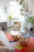 Coffee tables with glass tops and armchairs on colorful carpet, in the background ladder shelf in the living room