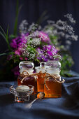 Honig in Gläsern dahinter Blumenstrauß