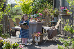 Little girl at the set table on the terrace with Easter decorations