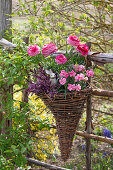 Willow wicker hanging from a fence with carnations (Dianthus) and ranunculus and a rabbit figurine