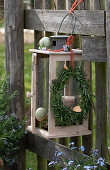 Easter decoration in the garden, Easter wreath and eggs hanging from a lantern on a fence, forget-me-not (Myosotis)