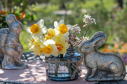 Blumenstrauß aus Narzissen (Narcissus) und blühende Zweige der Felsenbirne (Amelanchier) in Vase und Osterdekoration