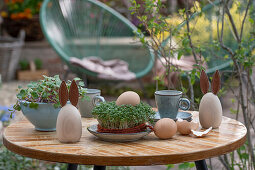Osterdekoration, Eier, gebastelte Hasenfiguren, Sprossen auf Terrassentisch