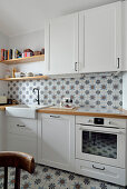 White fitted kitchen cabinets with dining area and patterned tiles