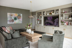 Grey sofa set, coffee table, large-format painting on the wall and shelving unit in the living room