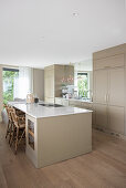 Kitchen island with cooktop in elegant beige kitchen