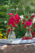 Bouquets of roses, candles and bulbs in glass vases on a wooden tray