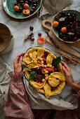 Tart with cherries and apricots. A woman is holding a fruit tart