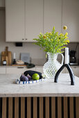 Candle, bouquet of flowers and fruit plate on kitchen island