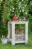 Muffins on a tiered pastry dessert stand, dishes, and glasses for the garden party on a wooden table