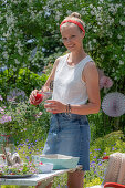 Sommerfest im Garten: Junge Frau gießt Erdbeergetränk in Glas