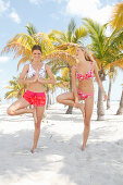 Girl friends doing yoga exercise on the beach