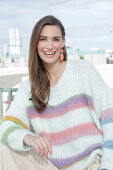 Young woman wearing a light knitted jumper with colorful stripes