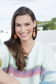 Young woman wearing a light knitted jumper with colorful stripes