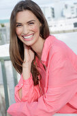 Young woman in salmon coloured shirt with pearl necklace