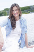 A young woman wearing a white t-shirt, a denim shirt and white trousers