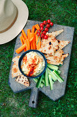 Grilled pita triangles with vegetables and dip on a large wooden board