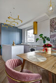 Dining table and pink velvet chair, kitchen with center island in the background