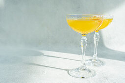 Glass of mimosa cocktail on stone background in sunny day
