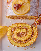 Festive sponge cake roll with jam and nut filling, candied lemon and spinning sugar