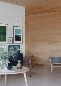 Coffee table and chairs in a bright room with picture gallery wall and passageway with a wood paneled wall and ceiling