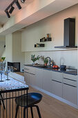 Kitchen in a subtle shade of grey and fireplace, counter with bar stools in the foreground