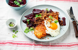 Breaded schnitzel with fried egg and beetroot salad