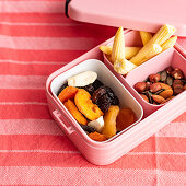 Getrocknete Früchte, Kernemischung und Maiskölbchen in einer Lunchbox