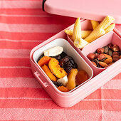 Dried fruits, seed mix and corn cobs in a lunch box