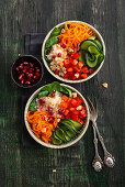 Raw vegetable salad with carrot, pepper, cucumber, white cabbage, lamb's lettuce, walnuts, and pomegranate seeds