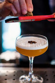 Barkeeper reibt Muskatnuss über Cocktail