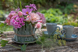Pink arrangement of roses, phlox, hydrangeas, and small teacups