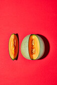 Cantaloupemelone, angeschnitten, auf rotem Untergrund