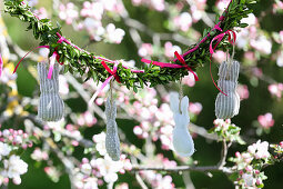 Homemade Easter bunny garland hanging from a blossoming fruit tree