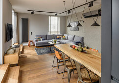 Offener Wohnraum mit Essbereich und Lounge in grauen Tönen, Wand in Betonoptik
