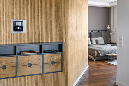 Hallway covered with raffia wallpaper, view into the bedroom with grey wallpaper