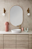 Modern Scandi-style bathroom in beige tones with curved sink with stone top and gold fittings