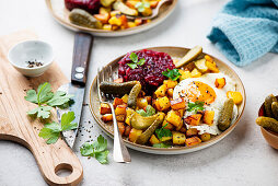 Fried potatoes with beet tartar, a fried egg and pickles