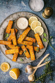 Golden brown polenta fries or chips, with dipping sauce, lemon and garlic
