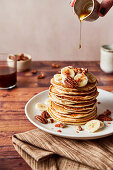 Banana Pecan Maple Syrup Drizzle Pour Pancakes on plate with coffee