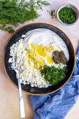 Zerbröckelter Feta-Käse, griechischer Joghurt, Knoblauchpüree, gehackter frischer Dill, Salz und getrocknete Minze